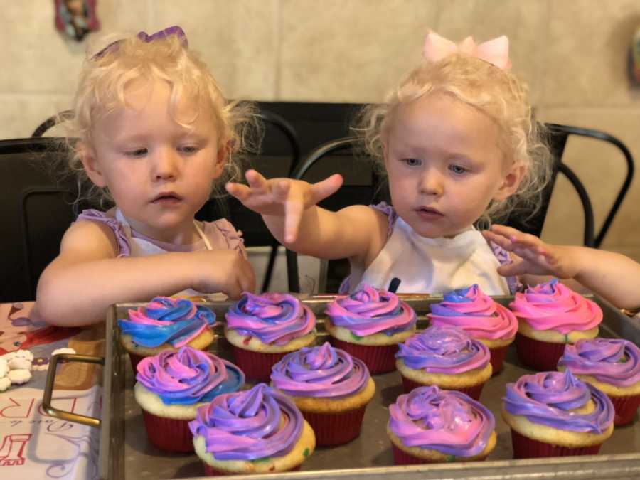 Twins sitting at table with birthday cupcakes they made sitting on tray in front of them