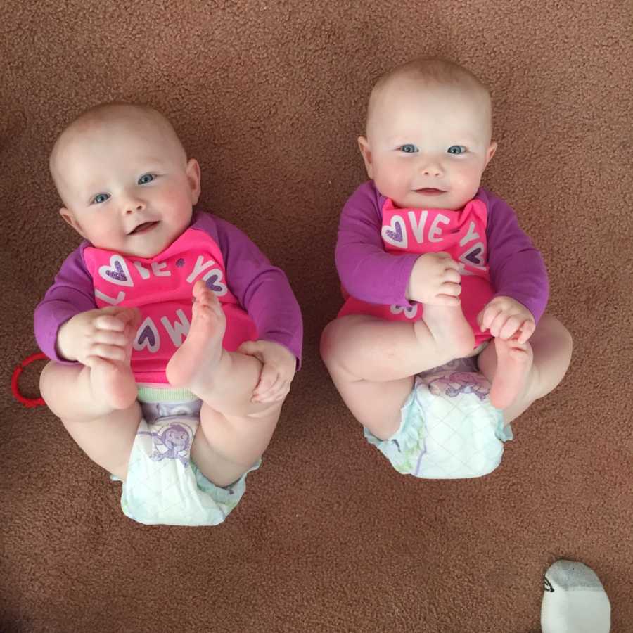 Infant twins who gave mother hard time on plane smiling while lying on floor holding their feet