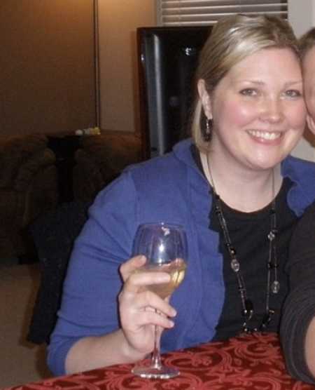 Woman who was a closet drunk smiling at table holding glass of wine