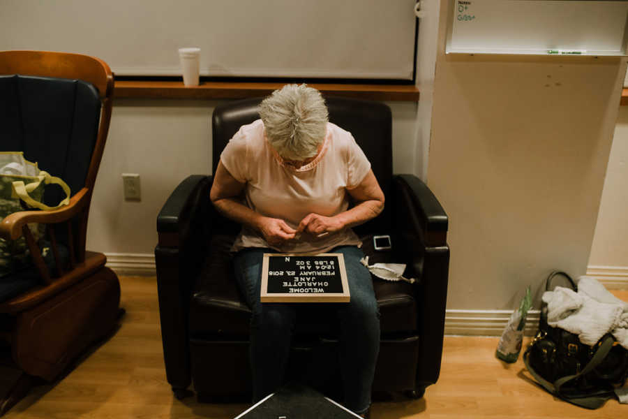 Woman works on making a sign announcing the birth of her grandchild while sitting in the hospital