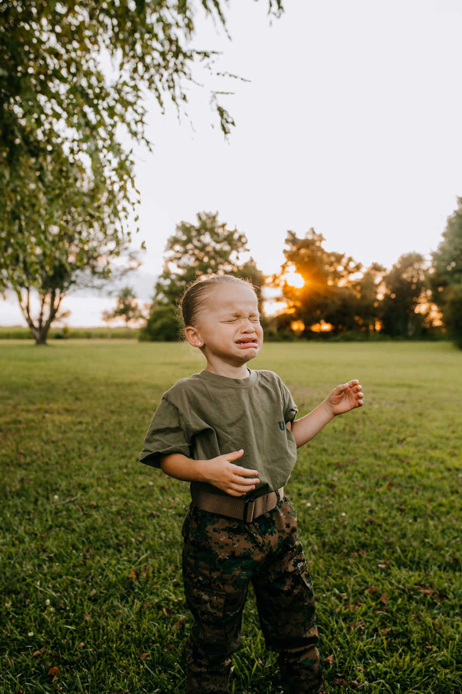 Little girl cries while wearing army training uniform