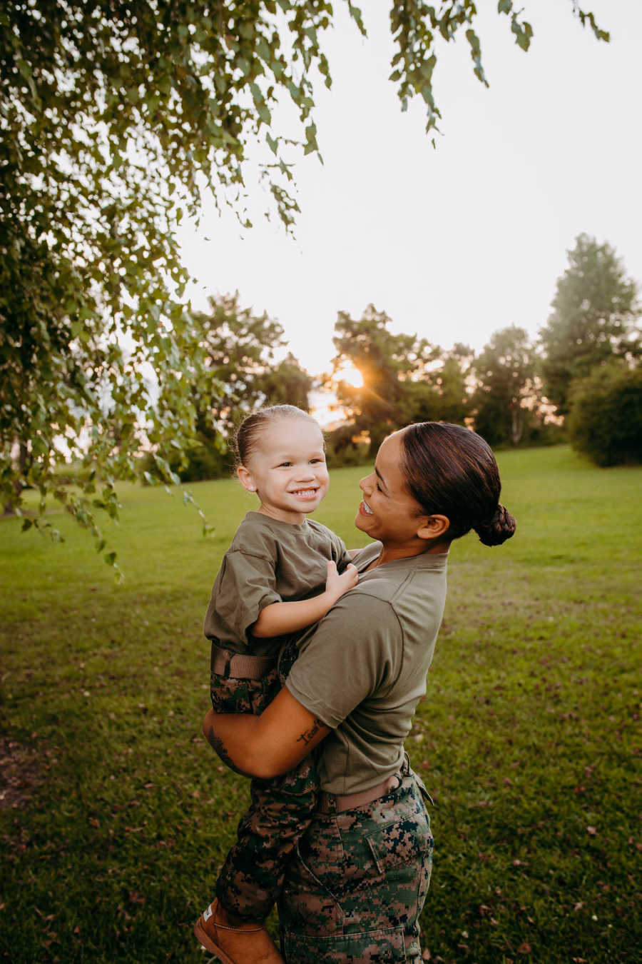 Mom and daughter smile during a photoshoot in matching uniforms