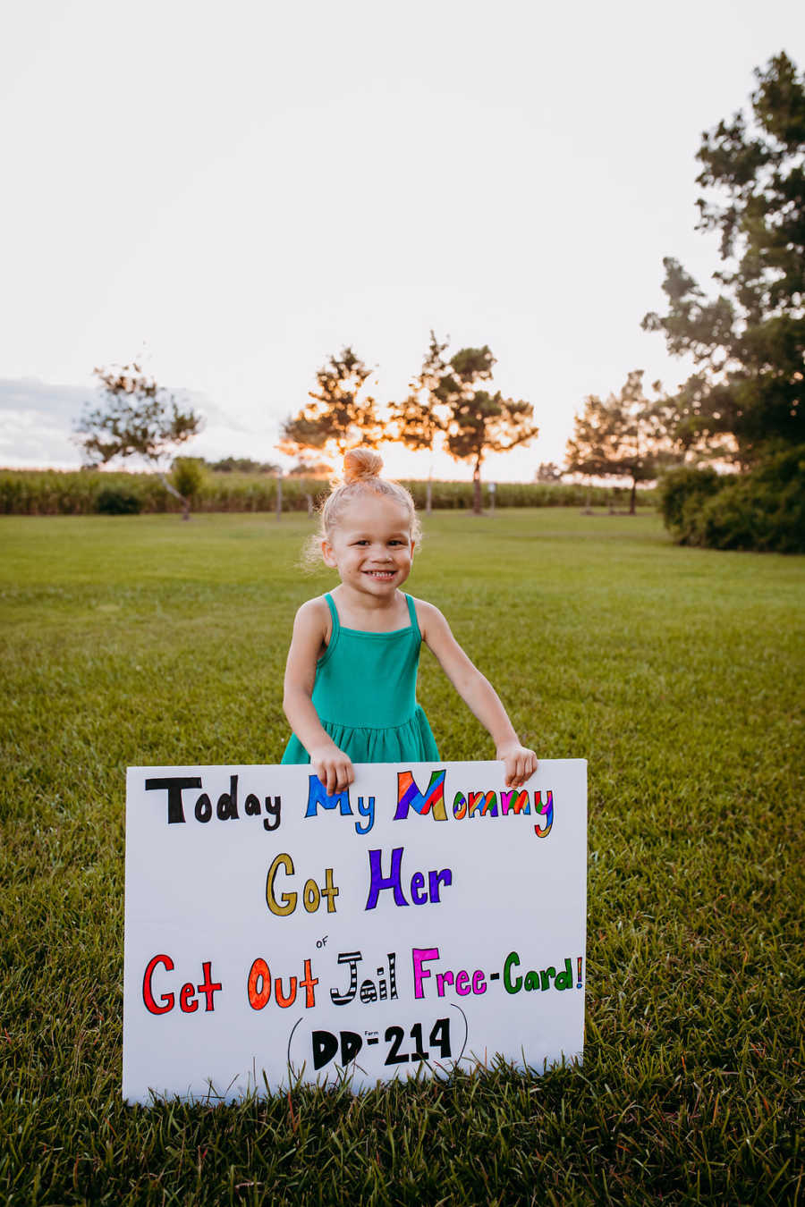 Little girl smiles big in blue dress while announcing her mom is retiring from the Marines