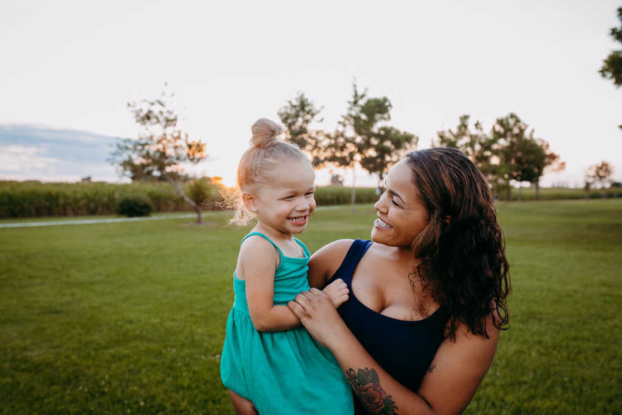 Mom and daughter smile during outdoor photoshoot in a park