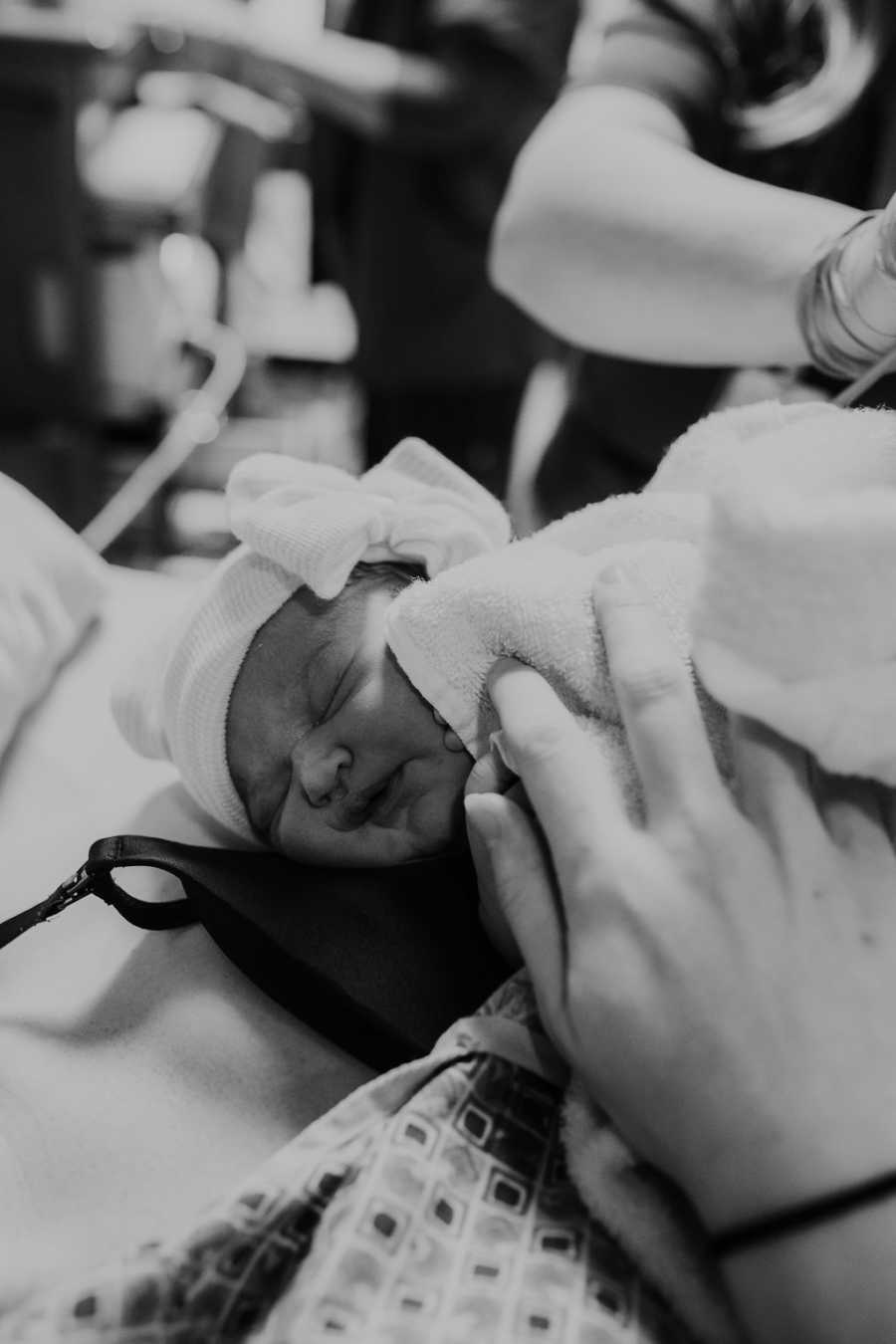 Newborn daughter sleeps in her mom's arms in the hospital