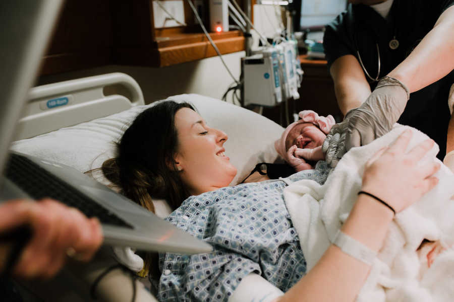 Woman smiles down at her newborn baby girl after 11 grueling hours of labor