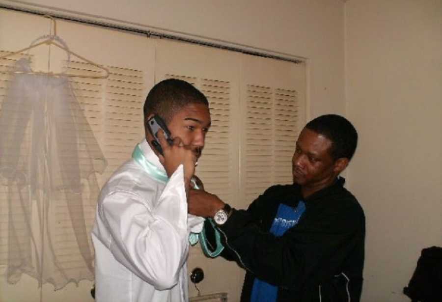 Teen on cell phone while stepdad who he will one day ask to adopt him ties his tie