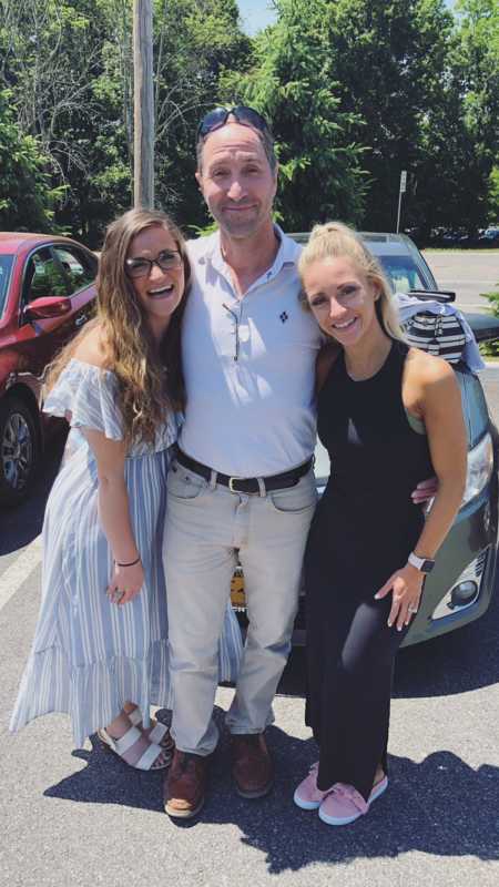 Woman takes a photo with her dad and sister while wearing their Sunday best