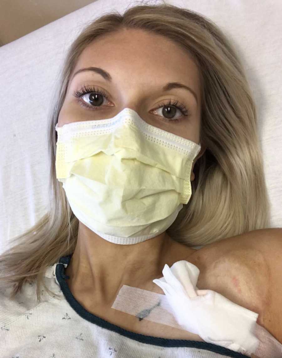 Woman with Ehlers-Danlos Syndrome lies in hospital bed with mask on and bandage on her shoulder