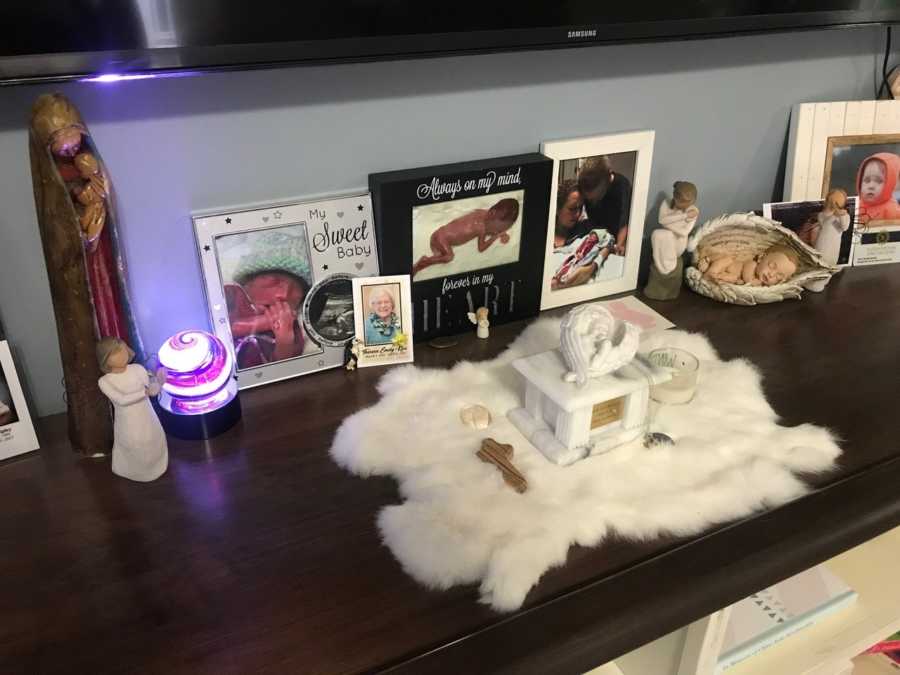 Box of ashes for baby who didn't make it surrounded by angel figurines and pictures of her