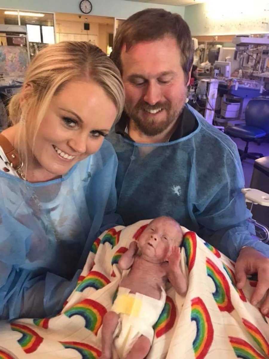 Mother and father smile holding preemie in blanket who never got to return home