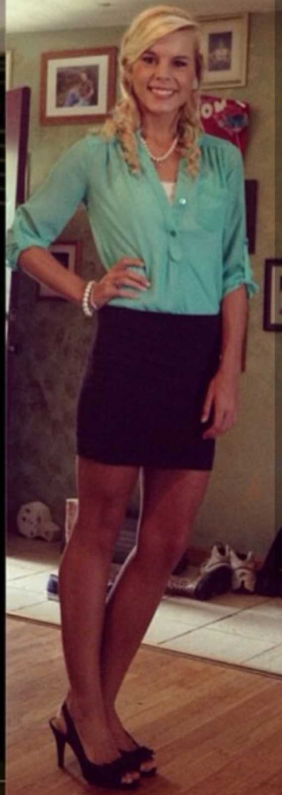 Young woman smiles for a photo in turquoise button-down shirt and black pencil skirt