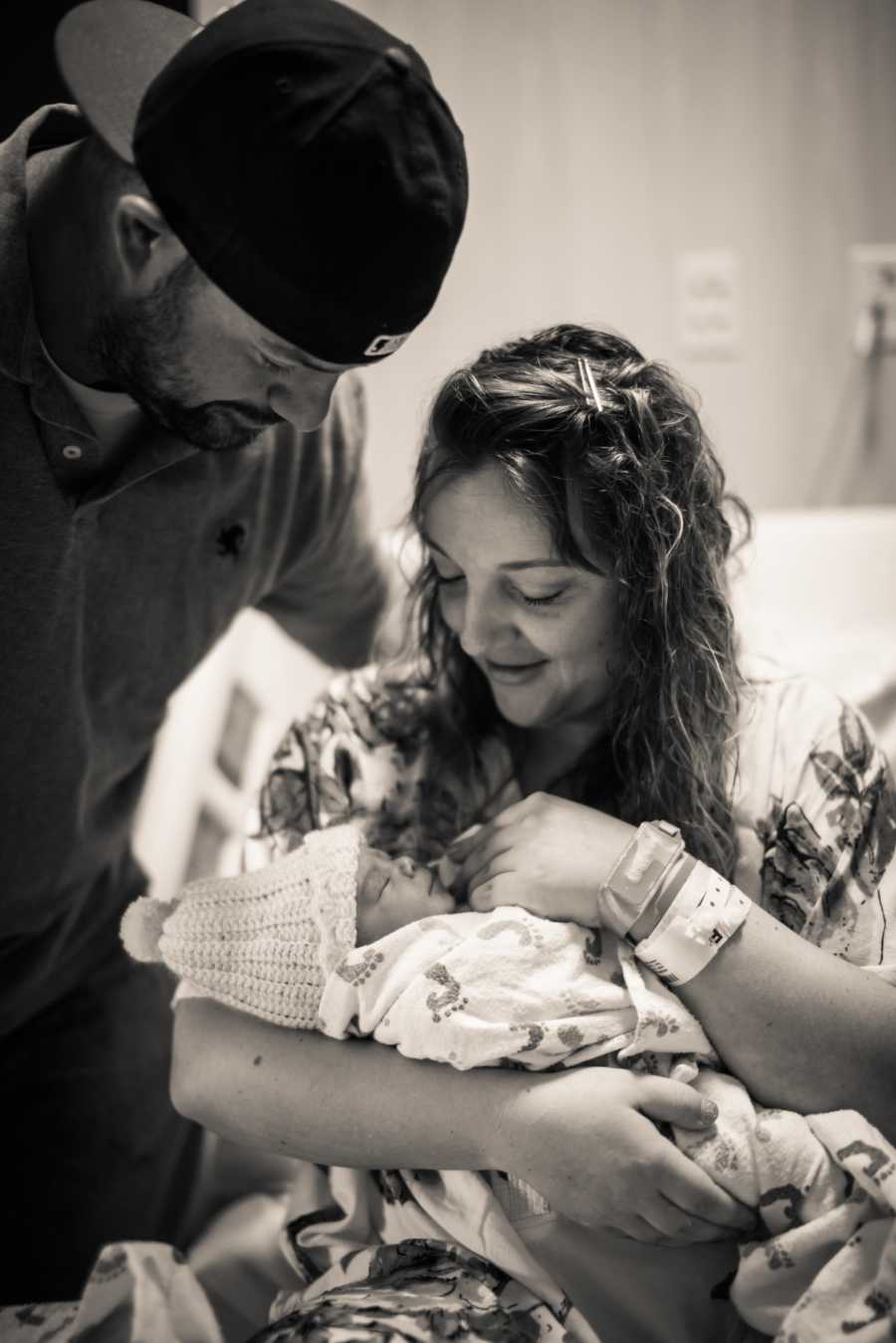 Wife who was scared to tell husband about fertility issues holds newborn in hospital with husband standing over her