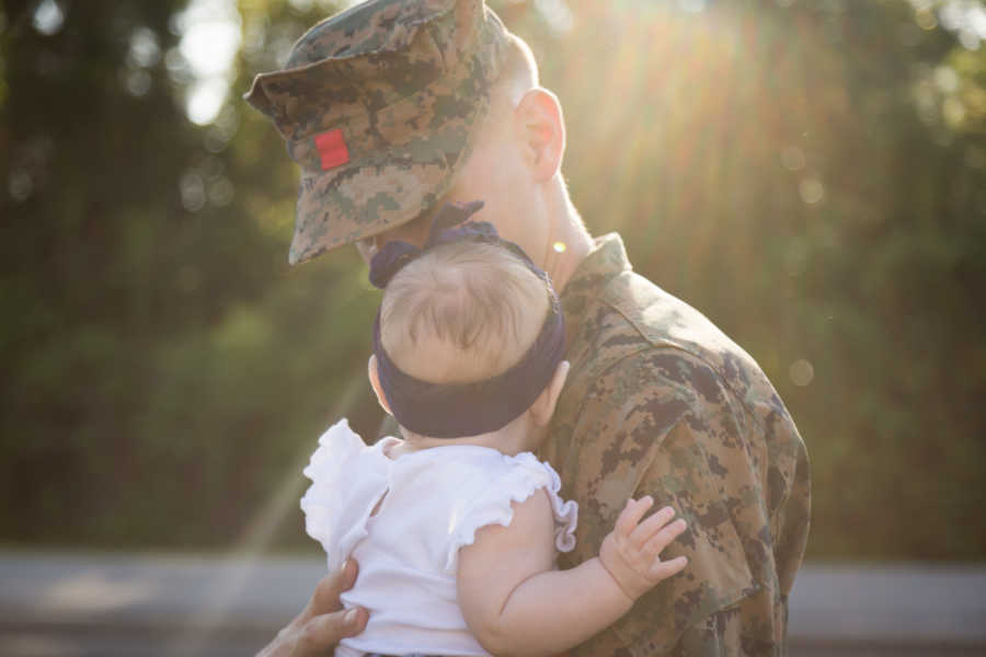 Soldier father holds baby daughter before he leaves for deployment