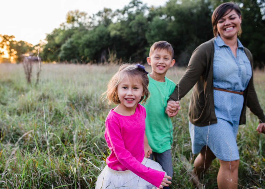 Woman smiling while walking in field with foster son and daughter