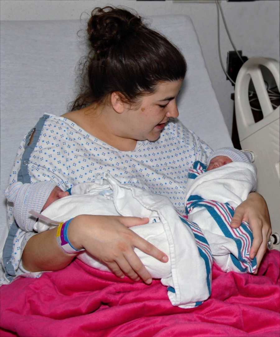 Surrogate sits in hospital bed holding newborn twins she just gave birth to