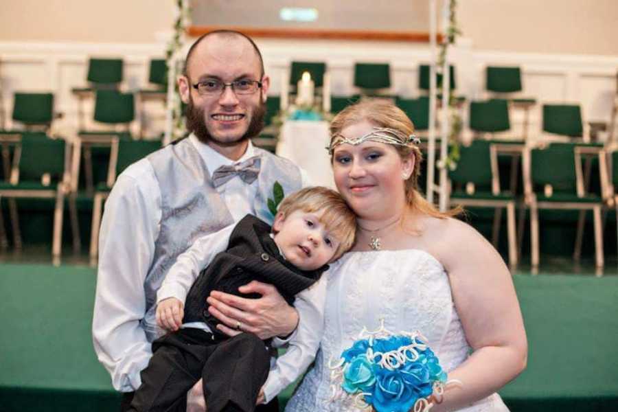 Groom with crohn's disease stands smiling with epileptic bride and her son at their wedding