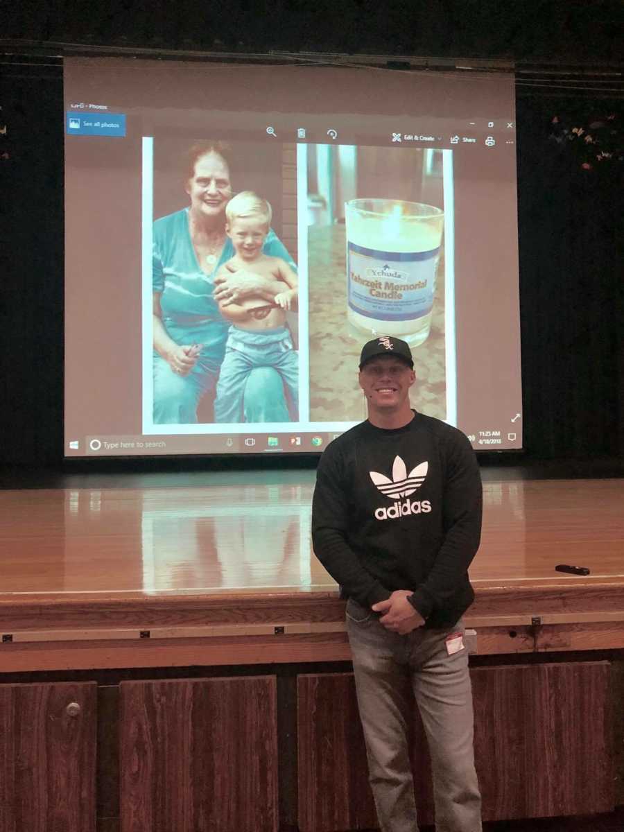 Man who got clean standing in front of stage and projector where he speaks on dangers of drug use