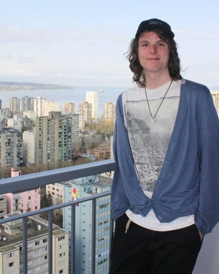 Teen addict smiling on balcony over looking city and body of water