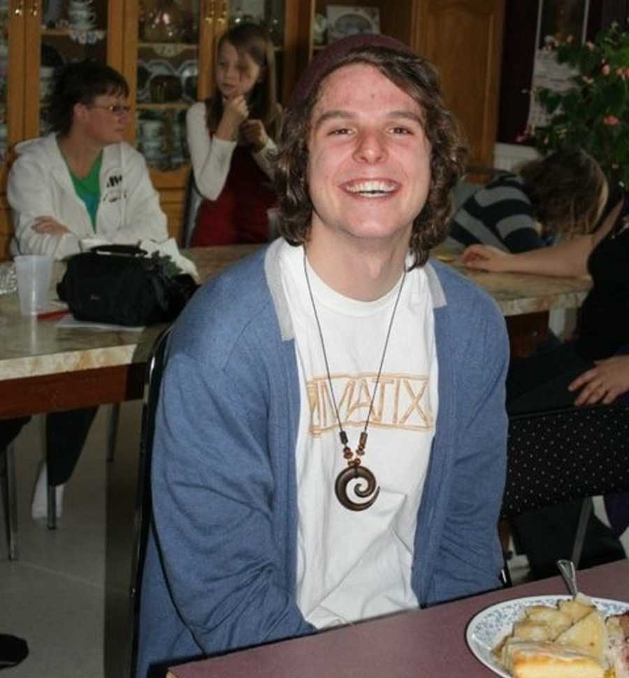 Man who says he was born an addict sitting at table smiling as teen