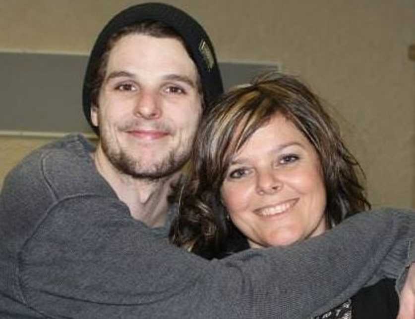 Young man who was an addict smiles with arms wrapped around mother