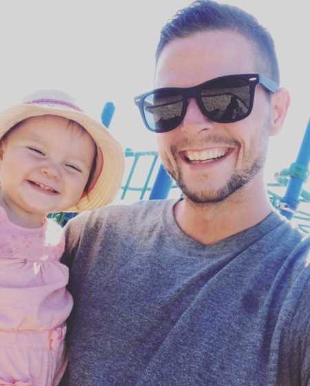 Man who got clean stands smiling with infant daughter in his arms