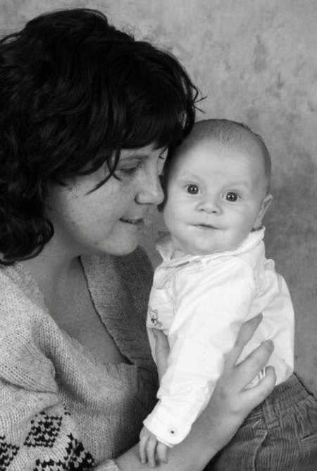 Mother who doesn't want son to grow up looks at him in her lap and he looks at camera