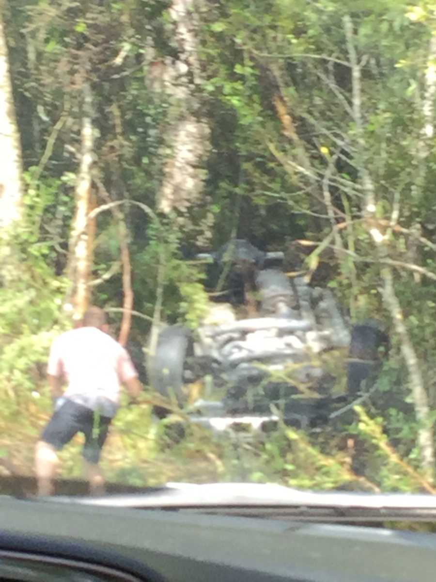 Car overturned in woods with man running to help