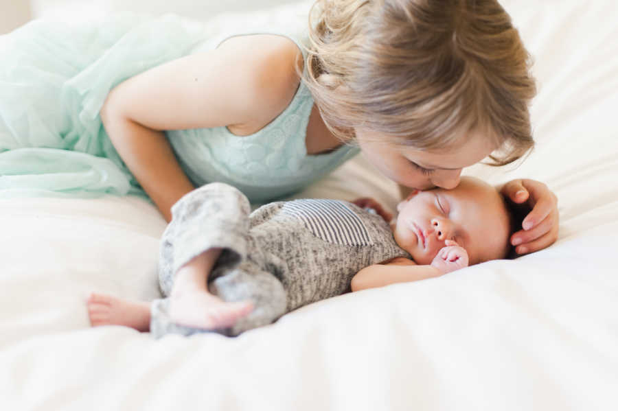 Big adopted sister kisses her newborn sibling on his forehead