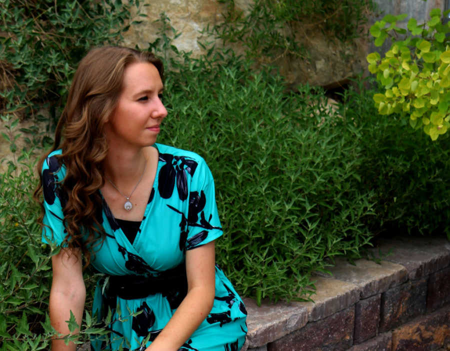 Woman sitting on stonewall staring over her shoulder after breaking off engagement