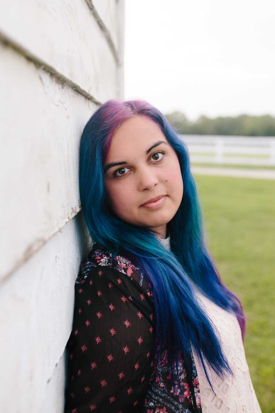 Twenty-two year old who has had over twenty suicide attempts in one year stands leaning against wall