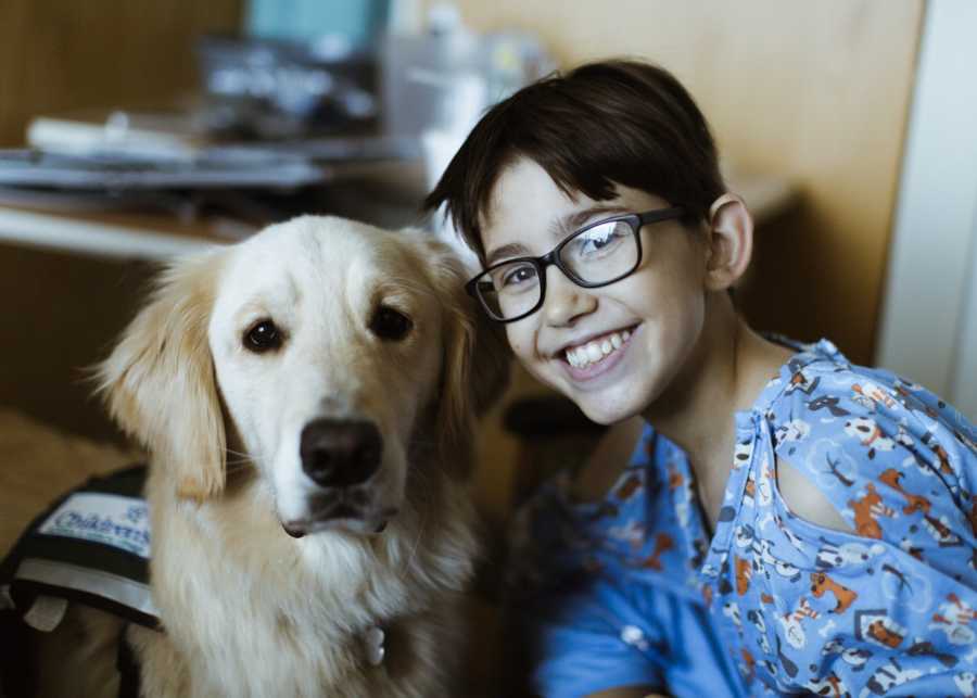 12 year old with heart issues smiles in hospital beside his golden retreiver