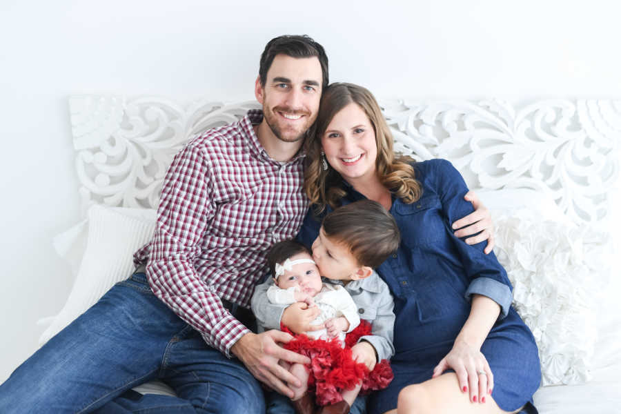 Husband wraps arm around wife who almost died at childbirth with son and newborn in their laps
