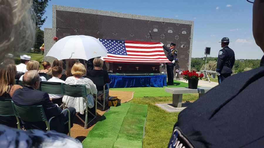 Police officers holding American flag over casket and police officer's funeral