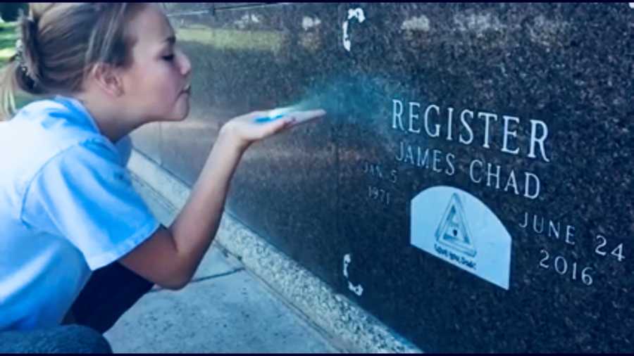 Daughter blows blue glitter onto her deceased father's gravestone