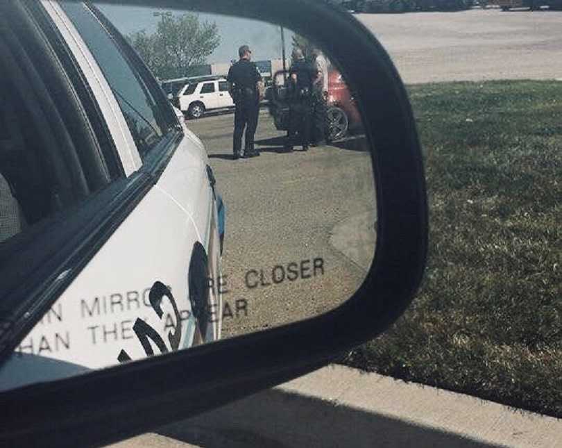 Woman takes a photo of her police officer husband in the side mirror of her car