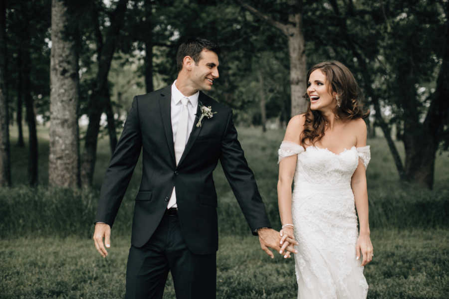 Bride and groom holding hands while looking at each other smiling