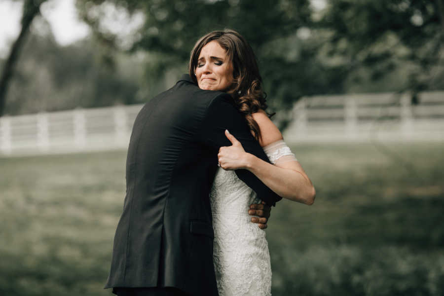 Bride and groom embrace while bride cries