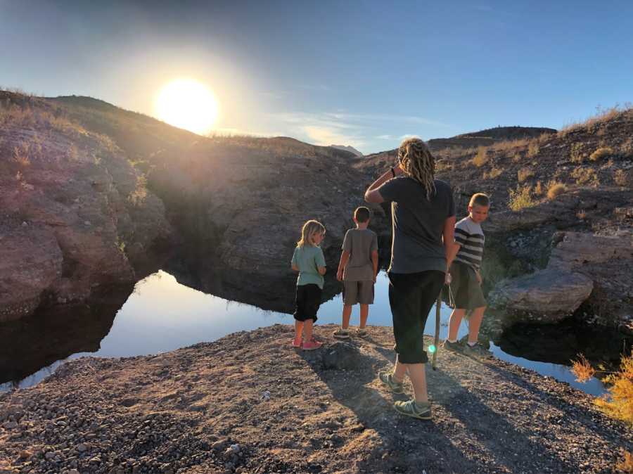 Mother whose family travels US in airstream stands on cliff with three children near body of water