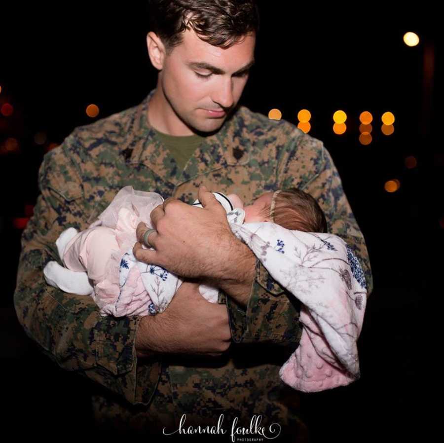 Marine husband and dad holds his newborn daughter for the first time after returning home