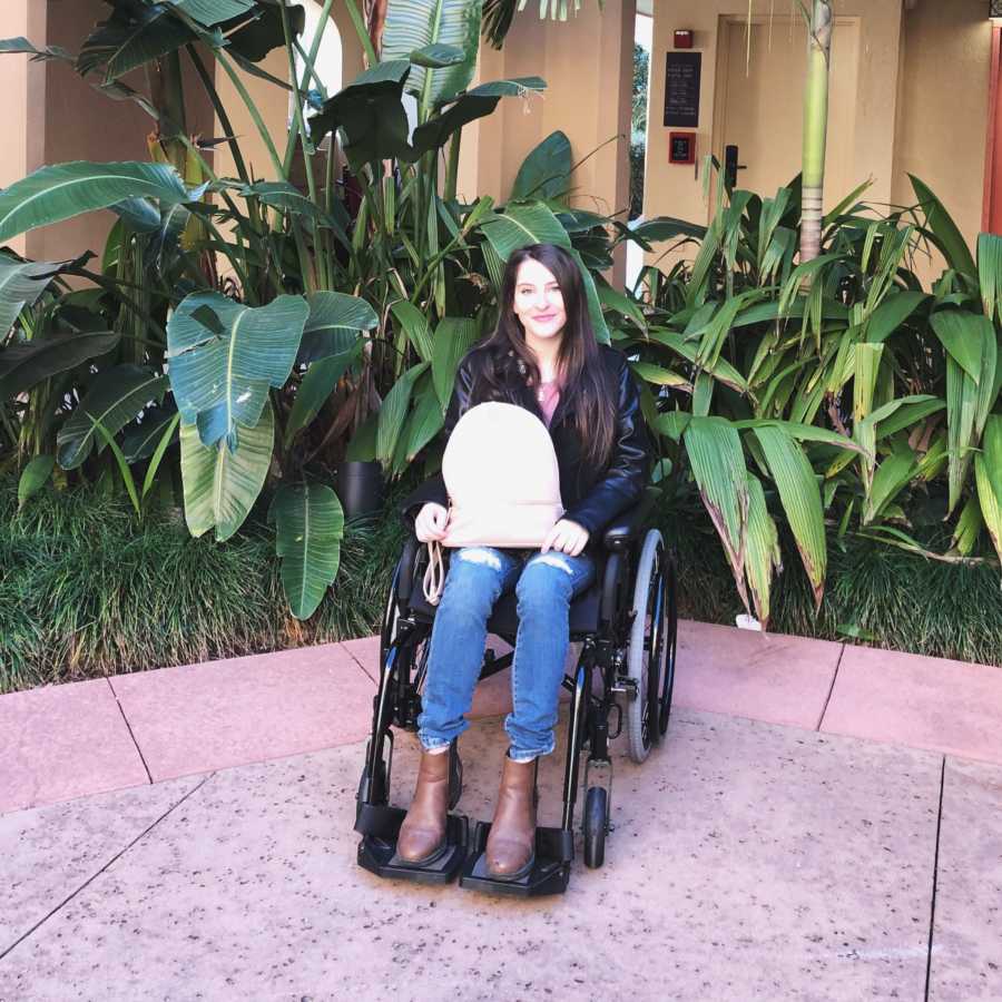 Woman with unknown illness sits in wheelchair in front of tropical plants
