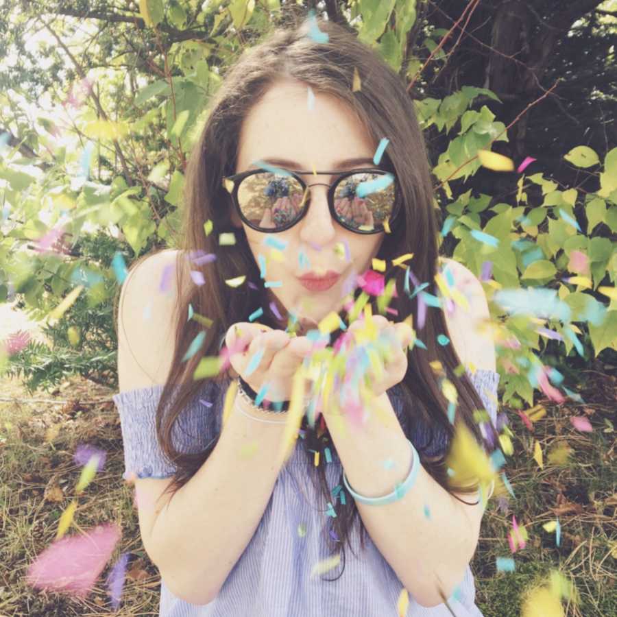 Woman with unknown illness blowing colorful confetti out of her hands