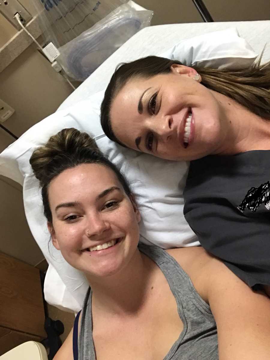 Woman diagnosed with POTS who also doubles as a pediatric ED employee lies in hospital bed smiling with colleague 