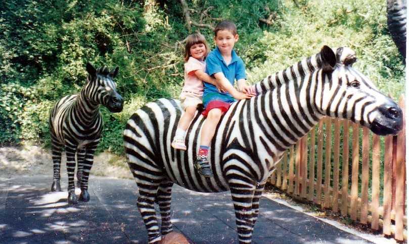 Brother and sister who were adopted sit on zebra statue