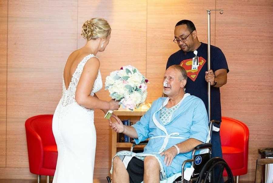 Father with pancreatitis sits in wheelchair holding daughter's hand who is in wedding dress