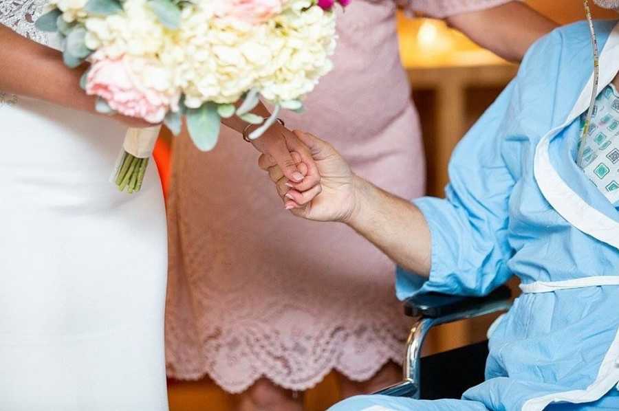 Close up of bride holding fathers hand who is in hospital with pancreatitis