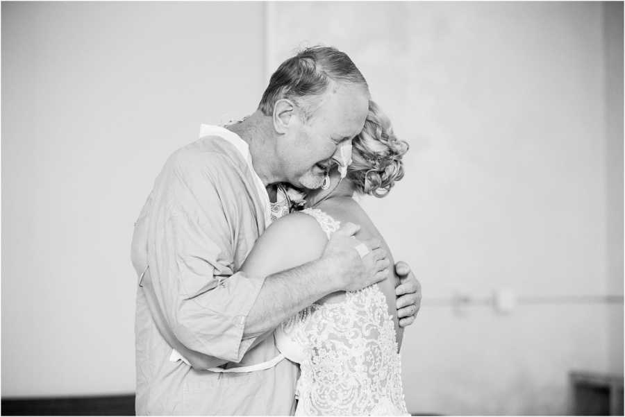 Father with pancreatitis stands crying hugging bride daughter