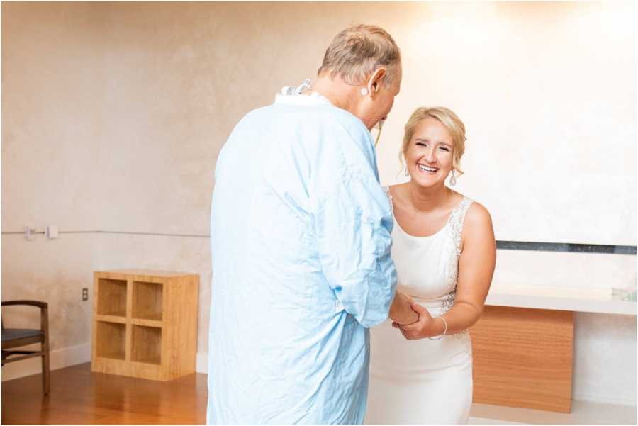 Bride smiles while holding hands with father who has pancreatitis in hospital