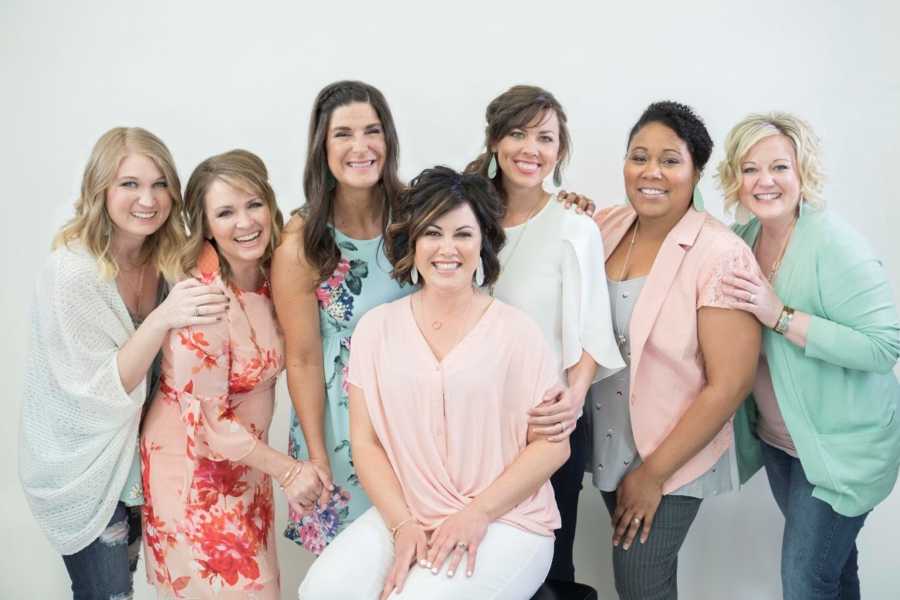 Woman who lost baby in womb sits on stool in front of row of women who also lost their children