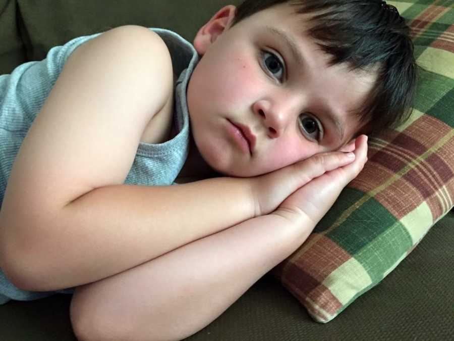 Little boy who wants to be a girl lying on hhis side on couch with head on pillow